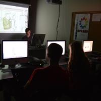 A professor and students in a digital media class, all in front of computers 