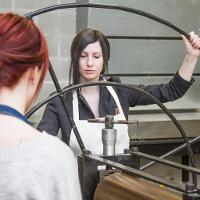 Two female students working with a large metal circle 