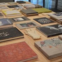 A desk with many notebooks and art books neatly arranged on top 