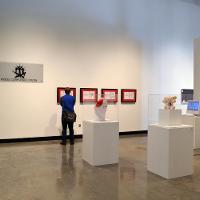 An art gallery, one onlooker next to a set of one of the paintings 