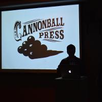 A silhouetted speaker presenting a slideshow saying "Cannonball Press" 