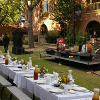 An outdoor bandstage with drums and instruments and a very long table set for a reception 