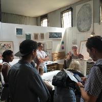 A female artist speaking to guests in her workshop 
