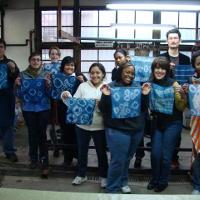 A group of smiling students, each holding a blue piece of fabric 