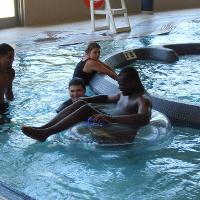 A group of campers swims in the lazy river in the CSU rec center. One camper is sitting on a float.
