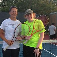 Two campers holding tennis rackets pose together for the camera.
