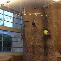 Two campers climb up the rock wall in the CSU rec center.