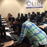 a computer lab with a number of students, one person helping a student
