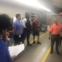 an older man explaining something to a group of students