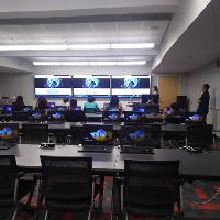 several students paying attention in class to a teacher with monitors at the front