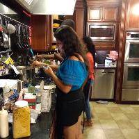 a girl standing in a kitchen and making something