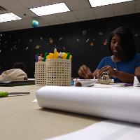 a girl sitting at a desk with markers