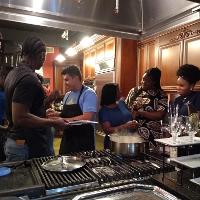 several students standing in a kitchen in front of a stove