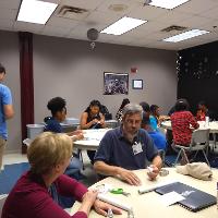 several students in a classroom, a male student talking to a female student