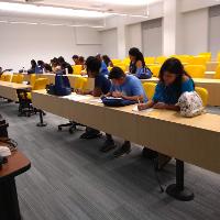 several students and adults sitting in a classroom, many are taking notes