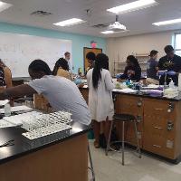 several students in a science lab with a teacher watching them