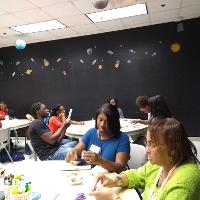 several students and adults sitting in a classroom at round tables