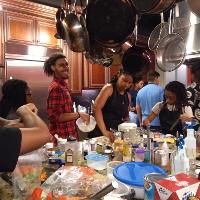 several students standing in a kitchen surrounded by cooking ingredients