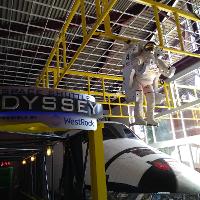 the entrance to an exhibit called A Space Shuttle Odyssey with a shuttle and astronaut