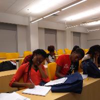 several students and adults sitting in a classroom writing in notebooks