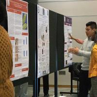 a male student discussing a presentation display to several people