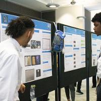 a male student discussing a presentation display to another male student