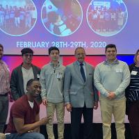 several people posing on a stage, one person kneeling