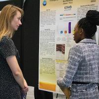 a female student discussing a presentation display to several people