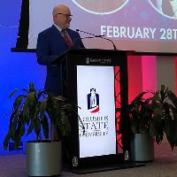 a man standing at a podium talking, looking at the audience