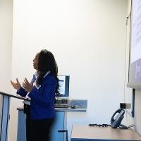 a woman standing and talking in front of a display