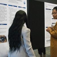 a female student with her back turned discussing a presentation with another woman