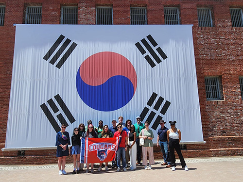 several people posing in front of a giant South Korean flag