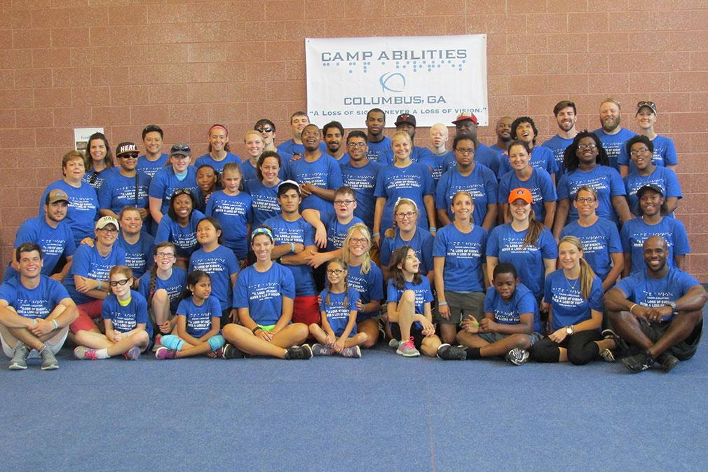 group photo of the 2016 Camp Abilities campers, posing with a large sign of the Camp Abilities logo