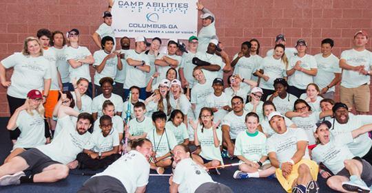 group photo of the 2018 Camp Abilities campers, some holding up a large sign of the Camp Abilities logo