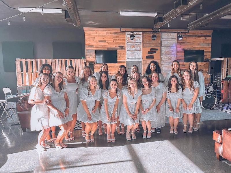 Sorority members posing, smiling, in matching dresses