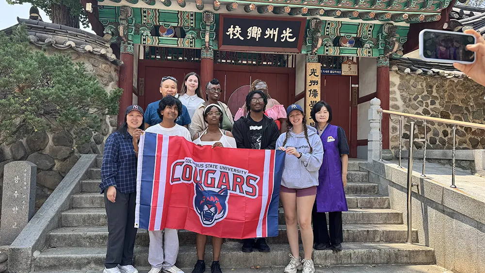 A group of CSU students holding a banner while they study abroad in Asia.