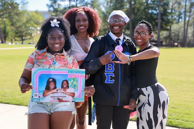 four greek life students posing for the camera outside on main campus