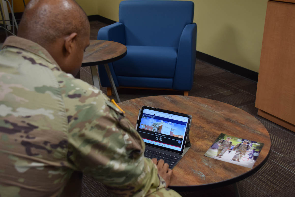 Over the shoulder view of a soldier using a tablet at a desk