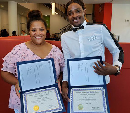 Two students hold an award