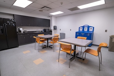 a breakroom with multiple tables and chairs