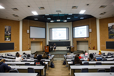 Several students in a lecture hall watching a presentation
