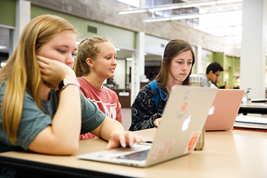 Three female students looking at laptops