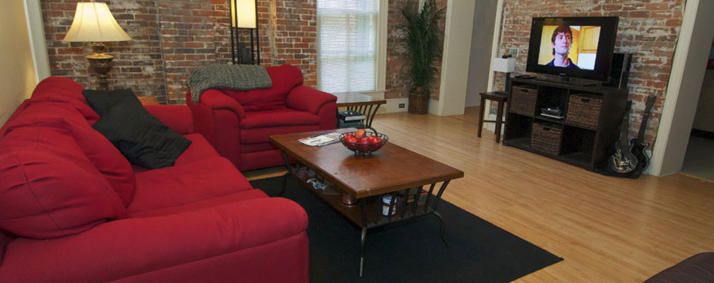 Common room with two red couches, a coffee table, and a TV on top of a media console