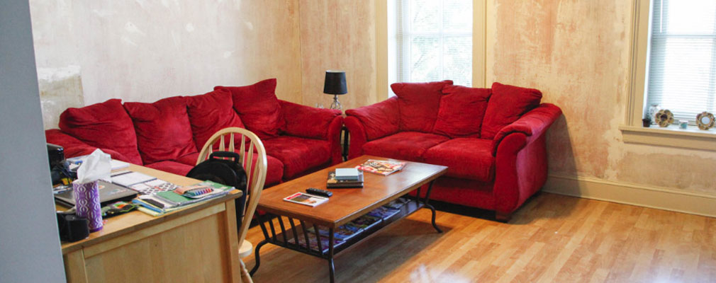common area with two red couches, a coffee table, a desk, and a large window
